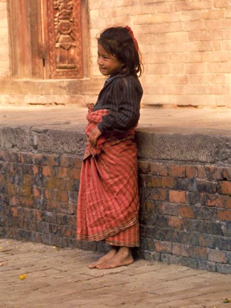 Little girl in Nepal by a wall