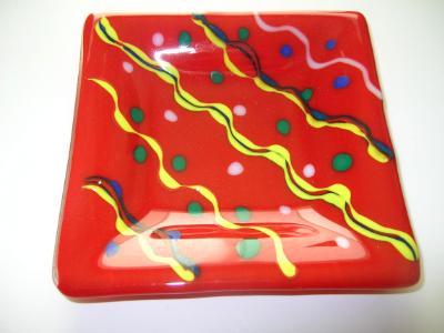 Bright red plate with yellow, blue, green and white decoration 