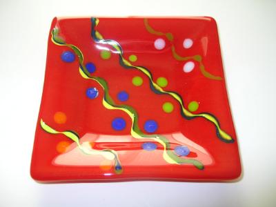 Bright red plate with blue, yellow, orange decoration 